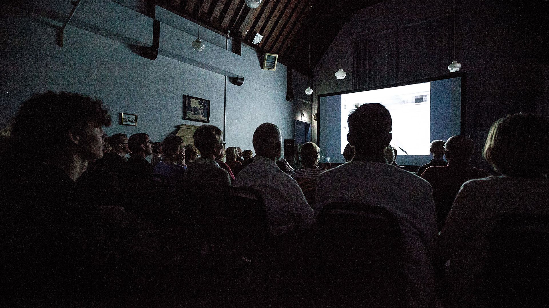 People sat in rows in front of a large projector.