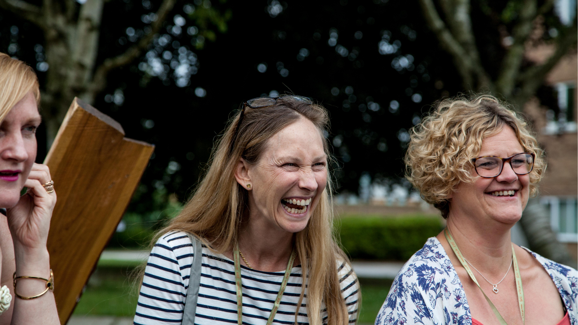 group of three people laughing and smiling together at something in the distance