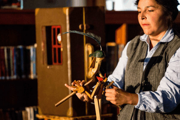 person operating a wooden sculpture of a man with a feather on his head