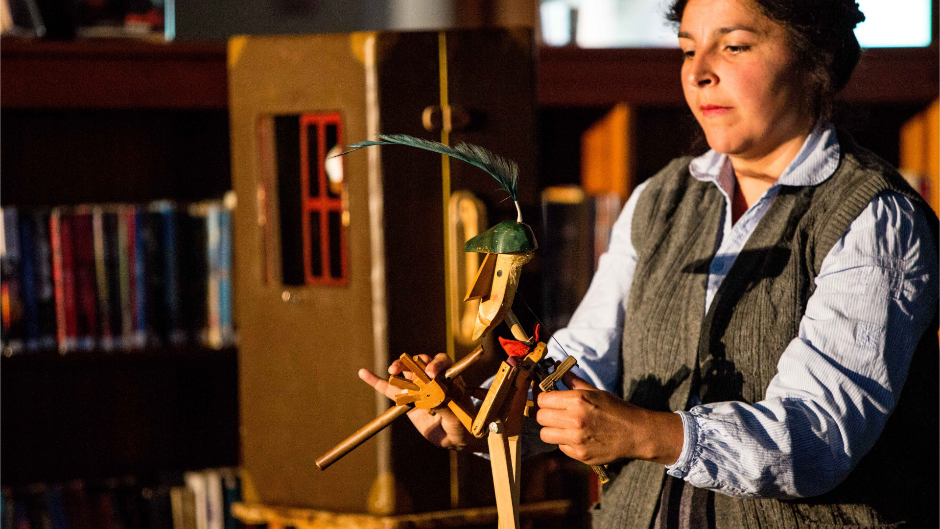 person operating a wooden sculpture of a man with a feather on his head